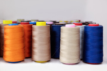 Many different spools of thread on white shelf in professional workshop