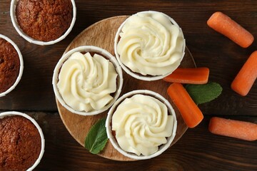 Tasty carrot muffins and fresh vegetables on wooden table, flat lay