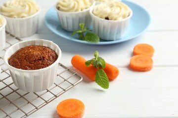 Delicious carrot muffins and fresh vegetables on white wooden table, closeup
