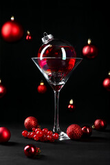 Creative presentation of Christmas cocktail in bauble and glass on black table