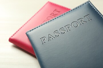Two passports in bright covers on white wooden table, closeup