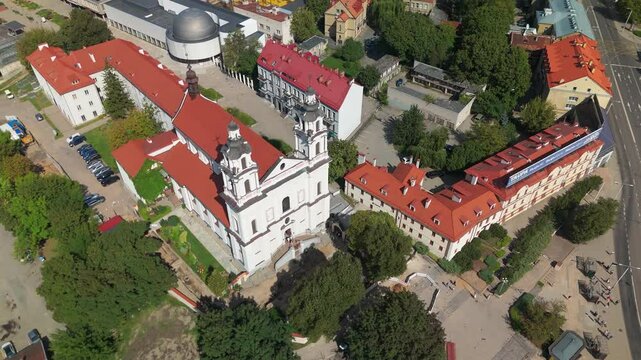 Drone ascending on church of St Raphael the Archangel and its urban surroundings with green trees