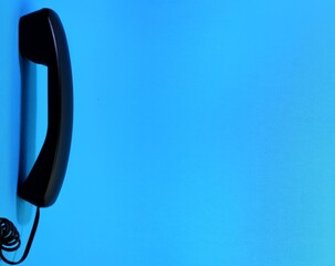 black telephone receiver isolated on blue background.