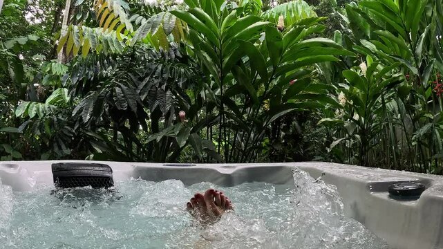 Woman's feet immersed in a hydromassage surrounded by nature, slow motion
