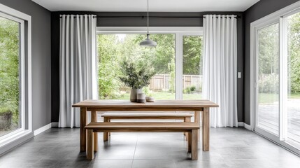 Fototapeta premium Modern dining room with wooden table, benches, and white curtains, overlooking a garden.
