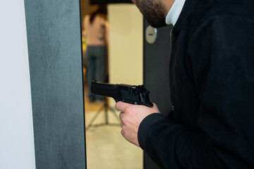 Obraz premium Attempted murder, man prepares to attack from the doorway with a gun in his hand