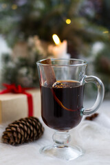 Winter hot drink mulled wine on the background of a Christmas tree with lights. New Year's decor, holiday