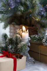 A craft gift box tied with a red bow stands under the Christmas tree. Fluffy branches of a fir tree, New Year
