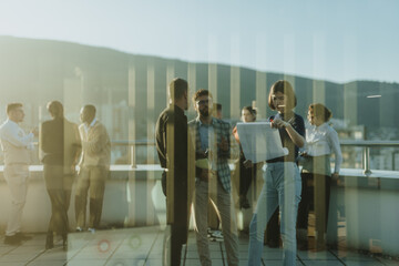 Group of business people standing on a tower balcony, engaged in a brainstorming session. The scene...