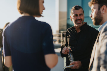Business colleagues gather on a high-rise balcony during sunset, engaging in a discussion about innovative project solutions, teamwork, and creative thinking.