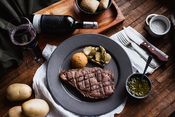  A piece of meat with its respective garnishes and wine