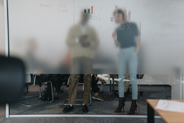 Colleagues participate in a brainstorming session behind a frosted glass wall. The environment is professional, encouraging collaboration among team members discussing business strategies and ideas.