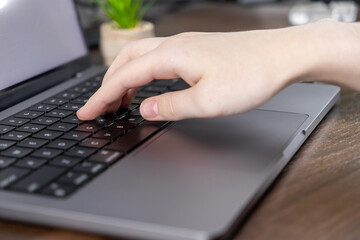 typing on laptop keyboard with fingers pressing keys in close-up view on a modern workspace