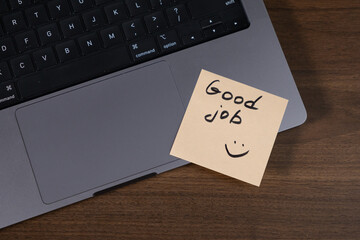 sticky note with good job message placed on laptop keyboard for motivation and encouragement