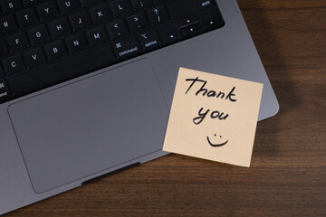 thank you note on laptop touchpad with smiley face for appreciation and workplace positivity