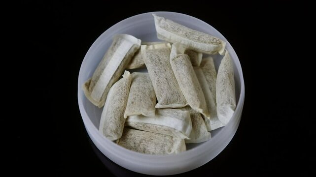 Snus nicotine tobacco close up, pack of tobacco for gum. unhealthy addiction. Man opening box with snus and taking one. 