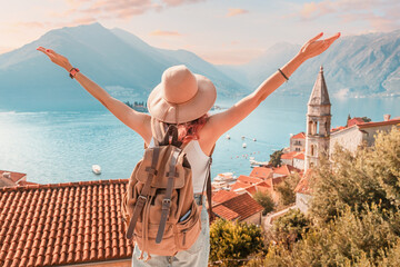 Young woman backpacker admiring the picturesque view of perast town and the bay of kotor in...