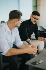 Obraz premium Two business workers having a casual conversation during a break at work, captured in a modern office environment. The image highlights a multicultural, multiracial workplace enjoying a relaxed