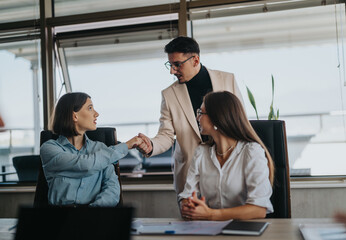 A multicultural group of business people is engaged in a meeting. They are actively discussing and shaking hands, symbolizing teamwork and collaboration in a modern office setting.