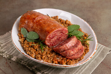 Italian Festive New  Year meal. Cotechino con lenticchie or pork sausage with Lentils cooked with vegetables on a green table.