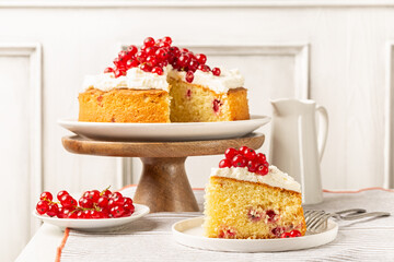 A piece of Yogurt cake with mascarpone cheese cream and Red currant.  Homemade bakery. White table and background.