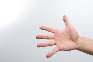 A person's hand is extended, fingers spread open, against a clean white backdrop.  The hand is positioned towards the camera, showcasing a simple yet expressive gesture.