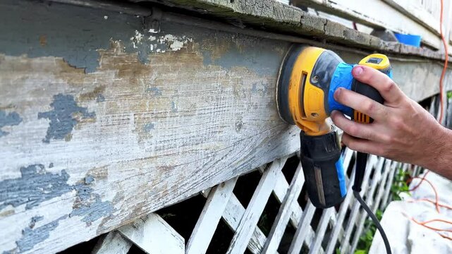 Sanding old paint from wood surfaces to prepare for renovation at a residential property