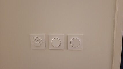 Ensemble de 2 interrupteurs muraux avec une prise de courant  sur mur blanc