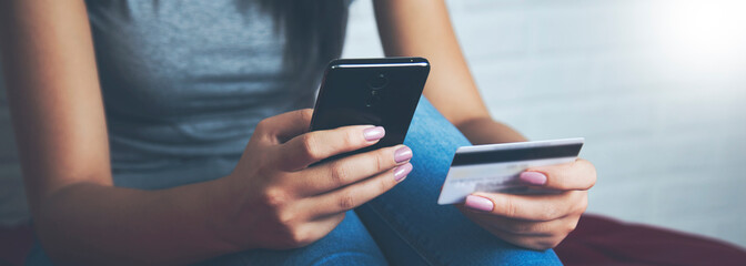 woman take credit card and look phone on the bed