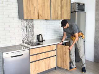 The carpenter finalizing the assembly of the kitchen shelf on the wall.