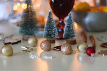 Various Christmas decorations, cookies, chocolate, nuts and tangerines, wine glasses and lit candles on the table. Holiday hygge at home. Selective focus.