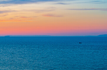 Defocused blue sea water surface stretches beyond horizon with hilltops. Fishing boat moving. Strait of Gibraltar global transport route located between Europe, Spain and Africa, Kingdom of Morocco