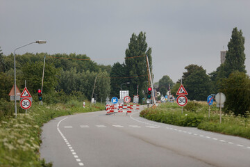 Road closure with temporary barriers and traffic signals.  30 mph speed limit signs visible. ...