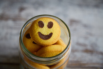 A jar filled with smiley cookies topped with a smiling face, close-up, good mood, homemade baking,...