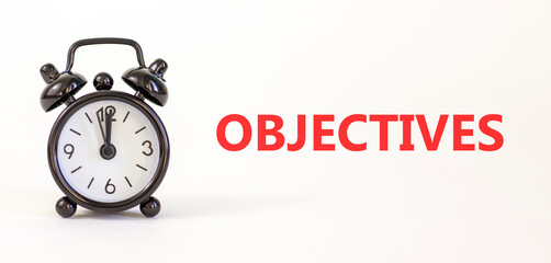 Objectives symbol. Concept word Objectives on beautiful white paper. Beautiful white paper background. Black alarm clock. Business objectives concept. Copy space.