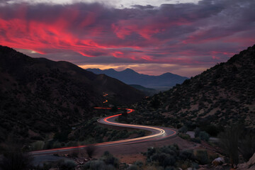 Mountain road at sunset, streaks of light from passing vehicles