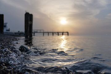 Small sea waves splashing at the beach with pebble at sunset, selective focus