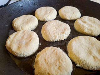 Homemade fried cheesecakes in a frying pan on the stove, top view