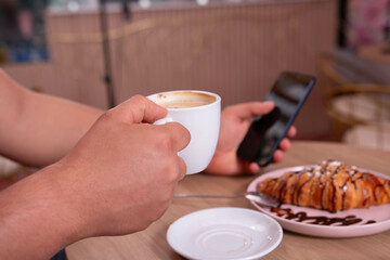 Close-up of a cup of coffee. Man enjoying his breakfast in a cafe