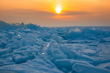 Frozen lake with blocks of ice. Ice hummocks. Sunset on a winter lake