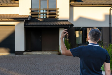 Young man with keys with new house background. Property lease real estate for relocation. Leasing insurance and purchase. Buying or renting