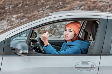 Angry female driver shaking fist at another car while driving