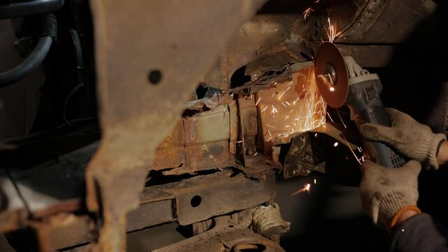 collision repairs service. mechanic grinding car body by grinder.male worker cuts metal van car body, car body repair