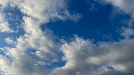 Bright blue sky with fluffy white clouds scattered across the horizon, creating a calm and serene atmosphere perfect for backgrounds and nature-themed visuals.