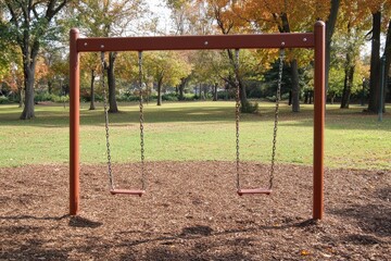 Deserted Play Area: A Pair of Empty Chain Swings in a Playground Evoking Childhood Memories