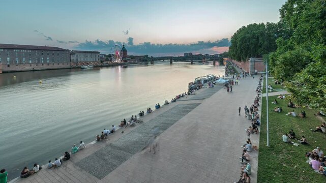 Aerial view of Port de la Daurade park along the Garonne River day to night transition timelapse in Toulouse, France. La Grave Hospital with Saint-Pierre Bridge during sunset with colorful clouds