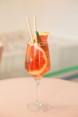Cold grapefruit cocktail with slices of fresh grapefruit decorated twig rosemary. Sunny day shadows. A refreshing summer mocktail