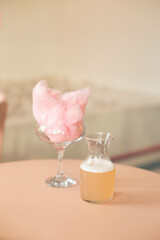 A beautiful pink cotton candy cocktail on a bar table with cotton candy pieces