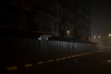 Fence at night. Driving between houses in dark. Evening city without people.