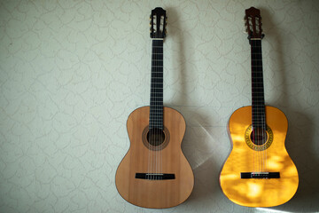 Two guitars hang on wall. Acoustic instrument. Classical guitars at home.